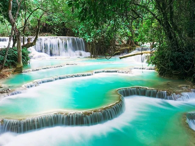 Wunderschöne Wasserfälle mit türkisfarbenem Wasser, das durch eine üppige Waldlandschaft fließt.