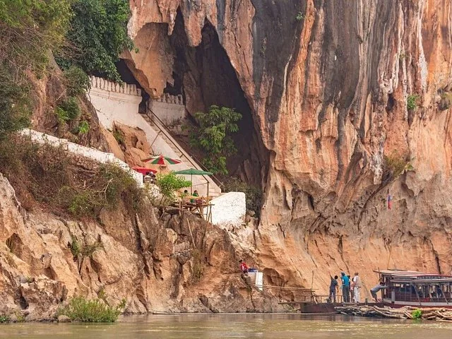 Boats docked near a white staircase leading up into a cave entrance on a cliff.