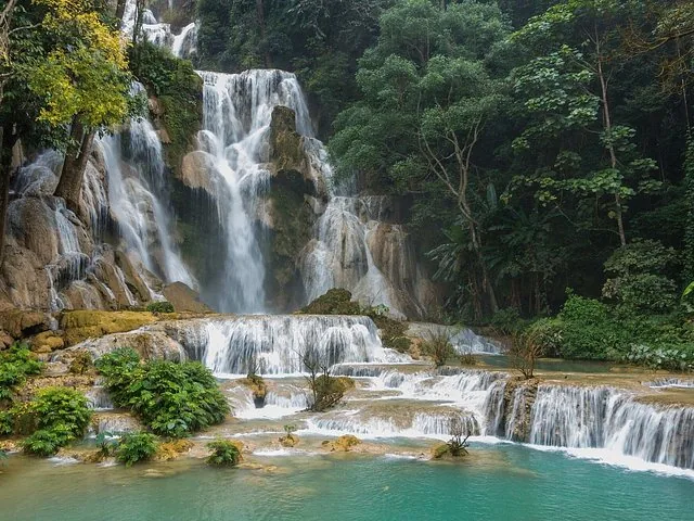 Scenic view of a multi-tiered waterfall cascading into a clear turquoise pool.