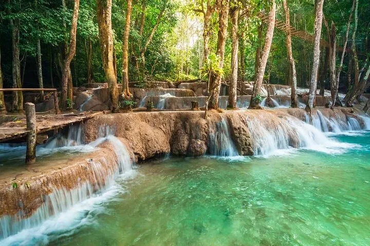 Klares türkisfarbenes Wasser fließt über Kalksteinterrassen in einem üppig grünen Wald.